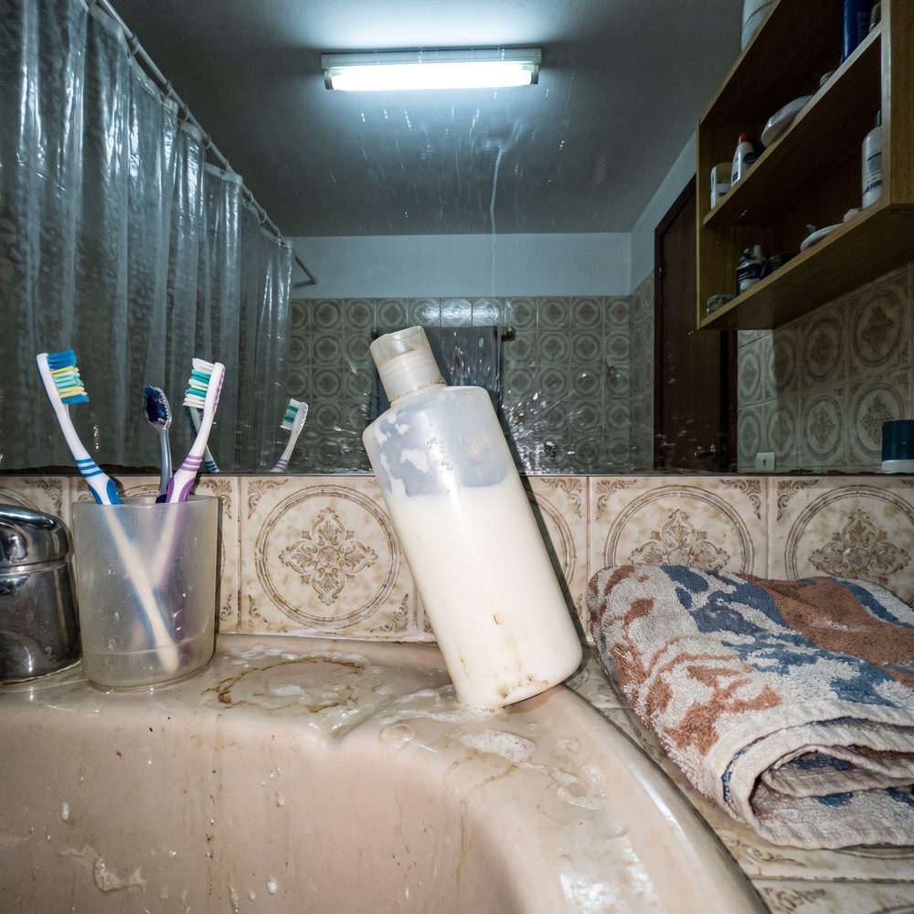 Peça de roupa fotografada torta, com sombra da lâmpada do teto e pé de cadeira no fundo